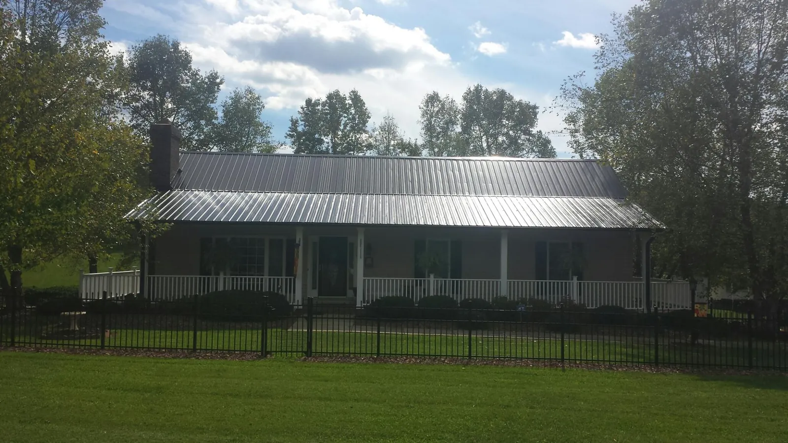 Gray metal roof on a brick ranch with a full width front porch — Gutter Guard Installation work by our crew in Williston