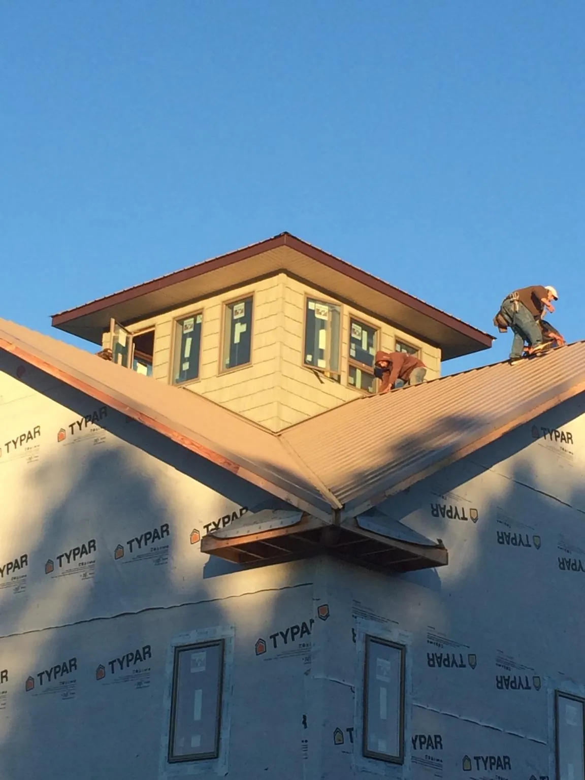 Roofers working around a rooftop cupola on a new metal roof at sunset — Roof Waterproofing in Williston by Roofing Brothers